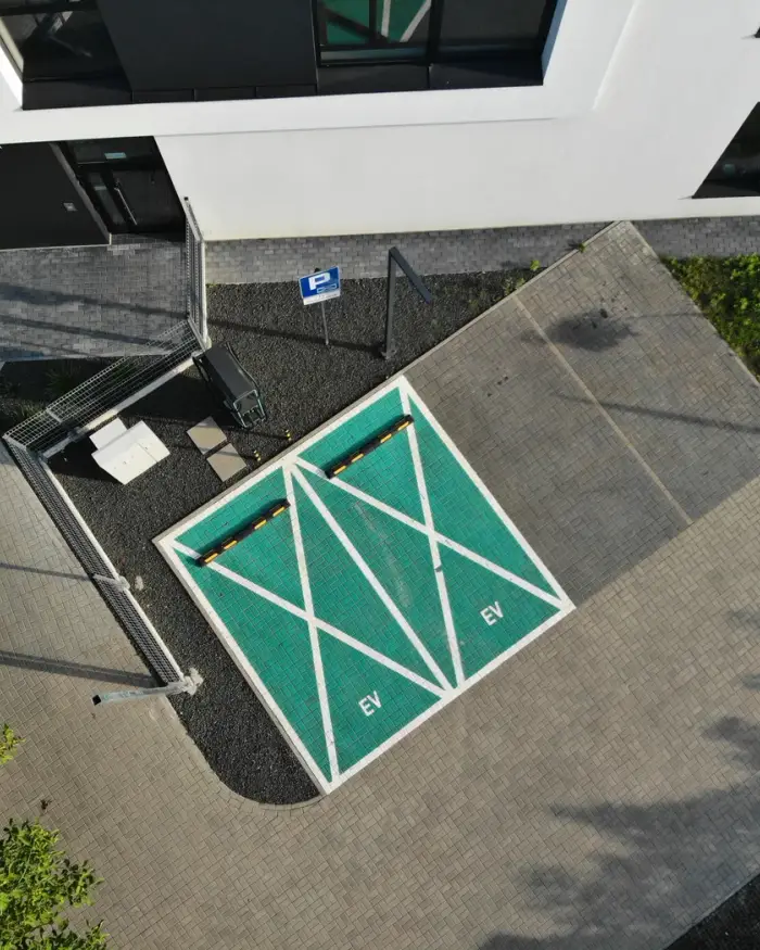 Ujęcie z góry na parking ze stacją ładowania ABC Energy i okoliczną zabudowę